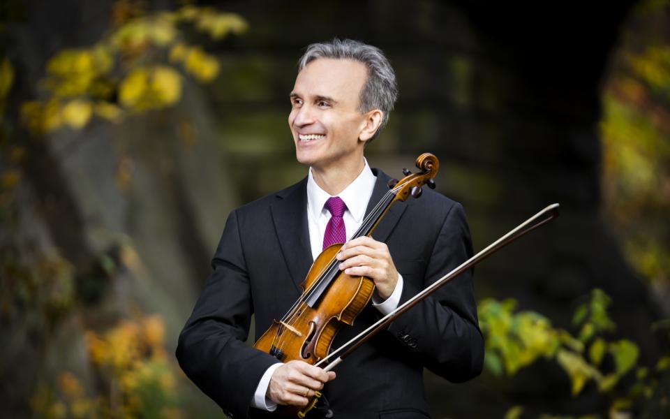 Violinist holding his instrument smiling in Central Park.