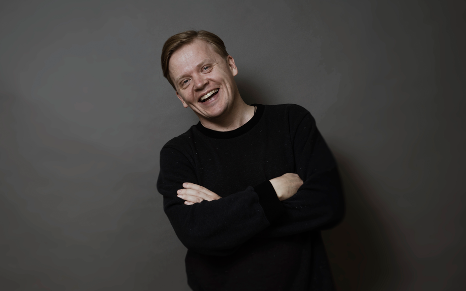 220509 Pekka Kuusisto c. Kaapo Kamu Violinist Pekka Kuusisto in black sweater smiling brightly.